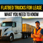 Professional truck driver standing confidently next to a white flatbed truck loaded with crates on an open highway at sunset — highlighting flatbed trucks for lease.